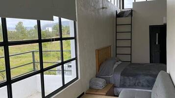 A bedroom with a large window, a bunk bed, and a sofa.