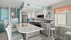 A modern kitchen with a central island, white cabinetry, and a microwave. - On the Boardwalk, 1st floor end unit, Ocean front, 4th Street, Ocean City, MD (Ocean City)