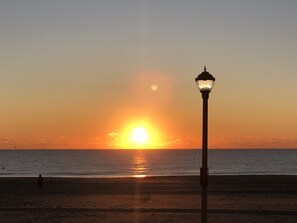 Un coucher de soleil sur l’océan, avec un lampadaire au premier plan.