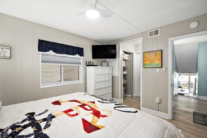 Une chambre à coucher comprenant un lit, une commode, un téléviseur et un placard.