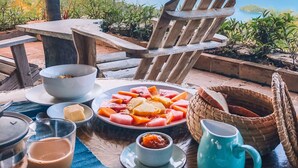 Una mesa dispuesta con comida y bebidas, con vistas panorámicas al mar y a las montañas.