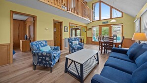 A spacious living area with a high ceiling, wooden balcony, and large windows. - Adorable Beach house in Duck with Hot Tub, Pet friendly.  Roof top deck! (Duck)