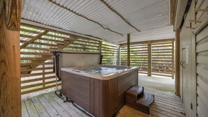 A hot tub in a covered outdoor area with wooden decking and a metal roof. - Adorable Beach house in Duck with Hot Tub, Pet friendly.  Roof top deck! (Duck)