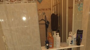 A bathroom with a washing machine, a sink, and toiletries on a shelf. - The secret of good taste. (Vaulx-en-Velin)