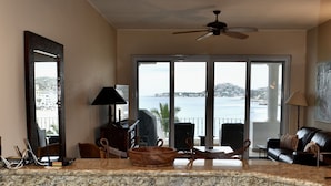 A kitchen with granite countertops, wooden cabinets, and a view of the sea.