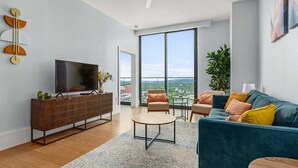 Un salon moderne doté d’un grand téléviseur, d’un canapé, d’une table basse et offrant une vue sur la ville.