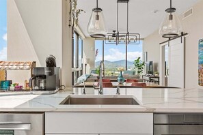 A modern kitchen with a large sink, a coffee maker, and pendant lights. - Blue Ridge Escape | Arras Vacation Rentals (Asheville)