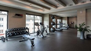 A modern gym with exercise equipment, large windows, and a digital clock.