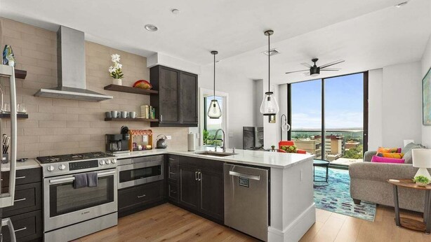 A modern kitchen with stainless steel appliances, a large island, and a view of the city.