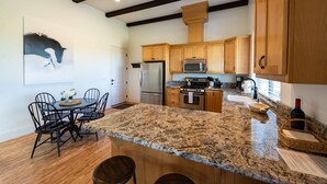 A kitchen with wooden cabinets, a granite countertop, a stainless steel refrigerator, and a dining area with a table and chairs. - Luxe 1BR/Studio w/Hot Tub on Templeton's Westside in the Heart of Wine Country! (Templeton)