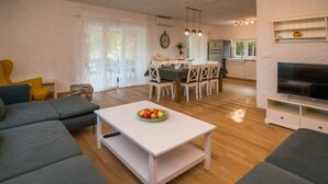 A modern living room with a white coffee table, grey sofas, and a dining area with a white table and chairs. - Holiday Home in Vrbnik with Terrace, Air condition, WIFI, Washing machine (4770-1) (Vrbnik)