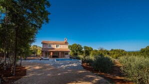 A two-story stone house with a tiled roof, a swimming pool, and a gravel driveway. - Holiday Home in Vrbnik with Terrace, Air condition, WIFI, Washing machine (4770-1) (Vrbnik)
