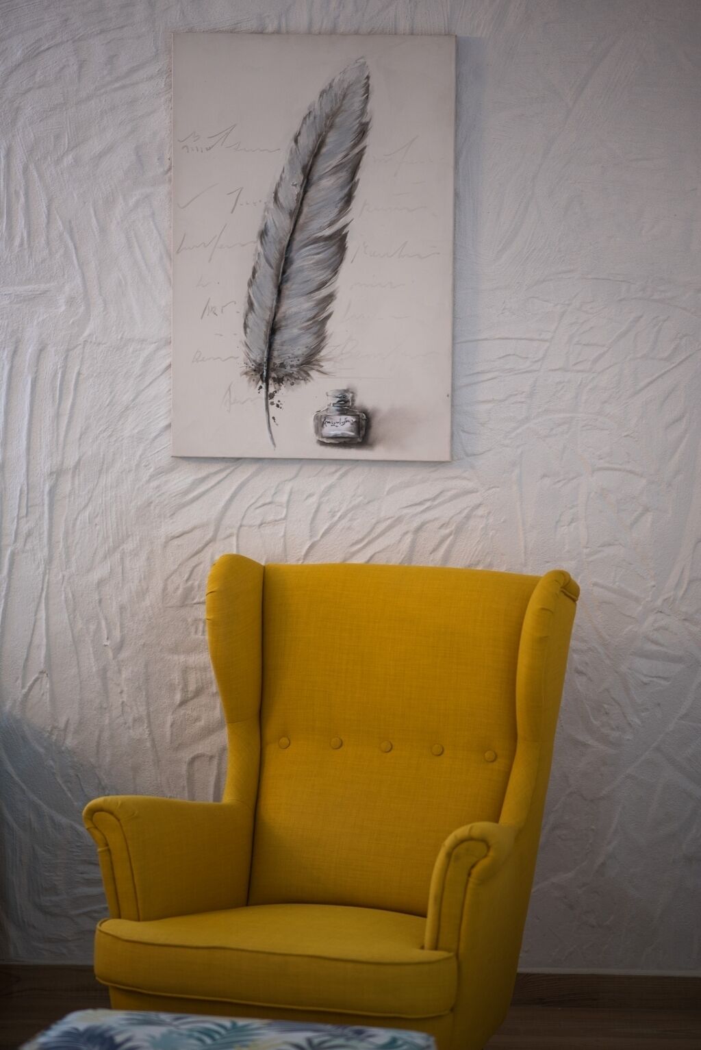 A yellow armchair in a room with a textured white wall.