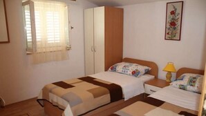 A bedroom with two beds, a wardrobe, a window with curtains, and a floral artwork on the wall. - Apartment in Pirovac with Terrace, Air condition, WIFI, Washing machine (4793-1) (Pirovac)