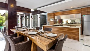 Una cucina moderna con isola centrale, elettrodomestici in acciaio inossidabile e zona pranzo con sedie in vimini e tavolo in legno.