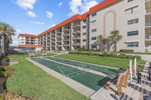 Hotel de varios pisos con un patio que incluye una cancha de shuffleboard.