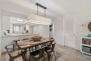Une cuisine moderne avec un coin repas, comprenant un grand îlot central, des chaises en bois et un luminaire suspendu.