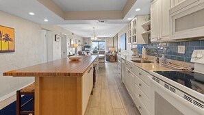 Una cocina moderna con una isla de madera, armarios blancos y salpicadero azul.