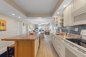 Una cocina moderna con una isla de madera, armarios blancos y salpicadero azul.