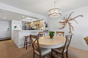 A modern kitchen with white cabinetry, a central island, and a dining area with a round table and chairs.