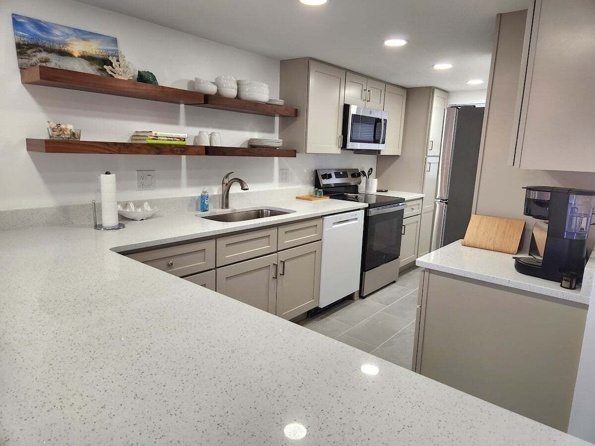 A modern kitchen with white cabinetry, a stainless steel sink, and a microwave.
