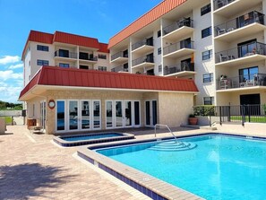 A multi-story building with a swimming pool, outdoor seating, and balconies. - 503 - Best Value No Balcony (New Smyrna Beach)