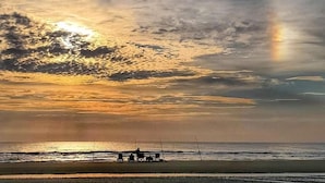 A beach scene with a sunset, a few people, and fishing rods. - 310 - Incredible ocean and pool views 1 bedroom (New Smyrna Beach)