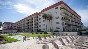 A multi-story hotel with balconies, a pool area, and outdoor seating. - 310 - Incredible ocean and pool views 1 bedroom (New Smyrna Beach)