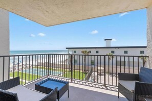 A balcony with a view of the beach and ocean, furnished with wicker chairs and a small table. - 310 - Incredible ocean and pool views 1 bedroom (New Smyrna Beach)