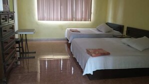 Habitación de hotel con dos camas, una mesita pequeña y un aparador.