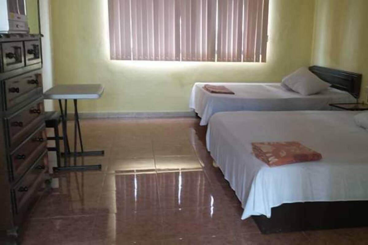 A hotel room with two beds, a small table, and a dresser.