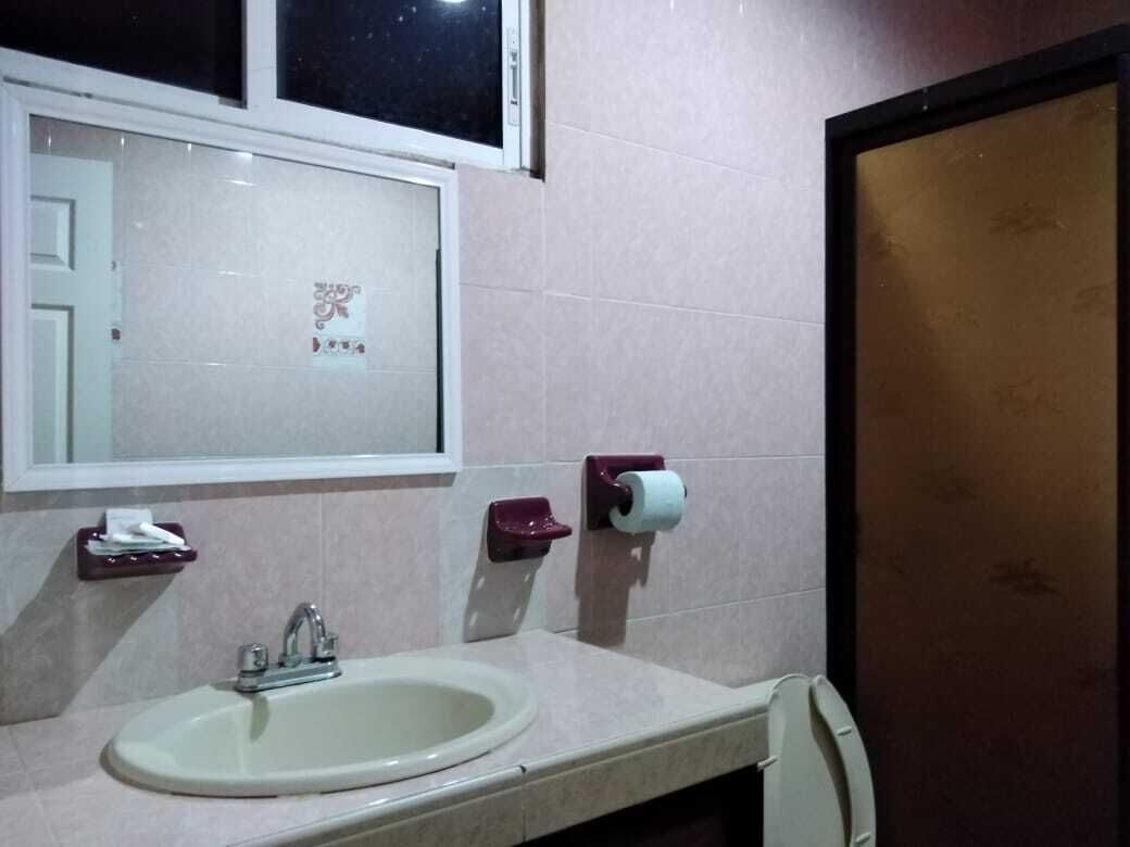 Un baño con lavamanos, espejo y dispensador de papel higiénico.