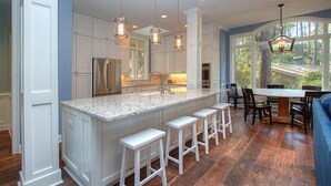 A spacious kitchen with a large island, white cabinetry, and pendant lighting.
