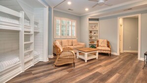 A room with bunk beds, a sofa, a coffee table, and a ceiling fan.