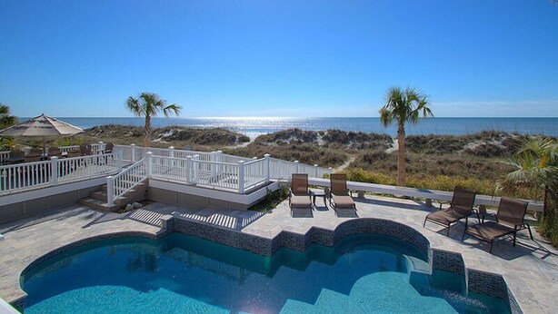 A pool with a view of the ocean, surrounded by lounge chairs and palm trees. - 123 Dune Ln - Oceanfront Home in N. Forest Beach w/ Private Pool & Beach Path (Hilton Head Island)