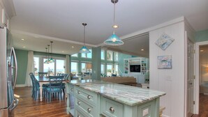 A spacious kitchen with a marble island, wooden cabinets, and pendant lighting. - 123 Dune Ln - Oceanfront Home in N. Forest Beach w/ Private Pool & Beach Path (Hilton Head Island)