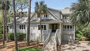 A two-story house with a front porch, a staircase, and a garage. - 26 Surf Scoter - 2nd Row Luxury Home in Sea Pines w/ Private Pool & Spa (Hilton Head Island)