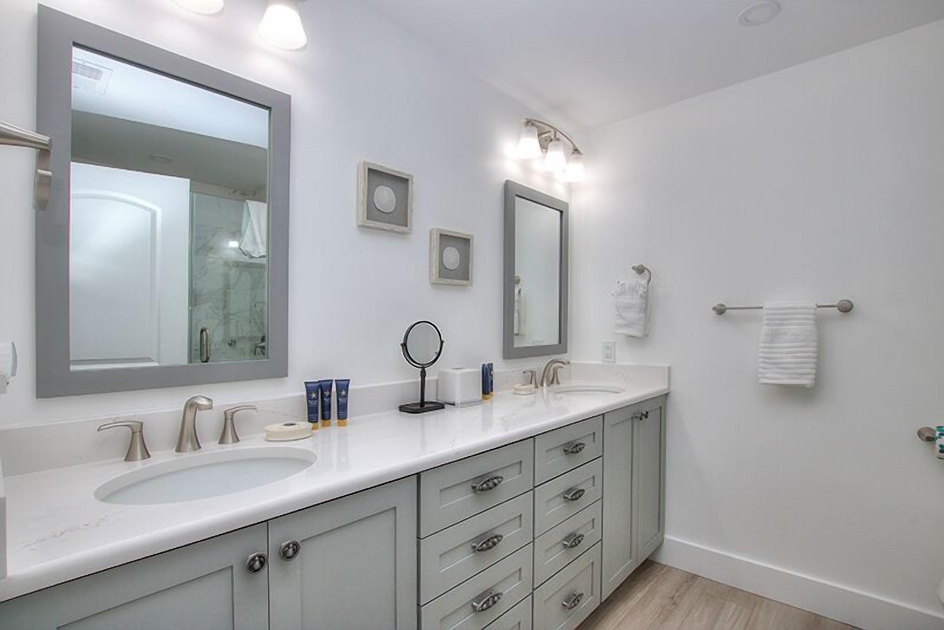 Une salle de bain moderne avec deux lavabos, un grand miroir et un porte-serviettes.