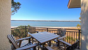 Eine Holzterrasse mit Tisch und Stühlen mit Blick auf einen Strand.