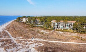 Un hôtel situé en bord de mer, composé de plusieurs bâtiments, doté d’une plage de sable et offrant une vue dégagée sur l’océan.