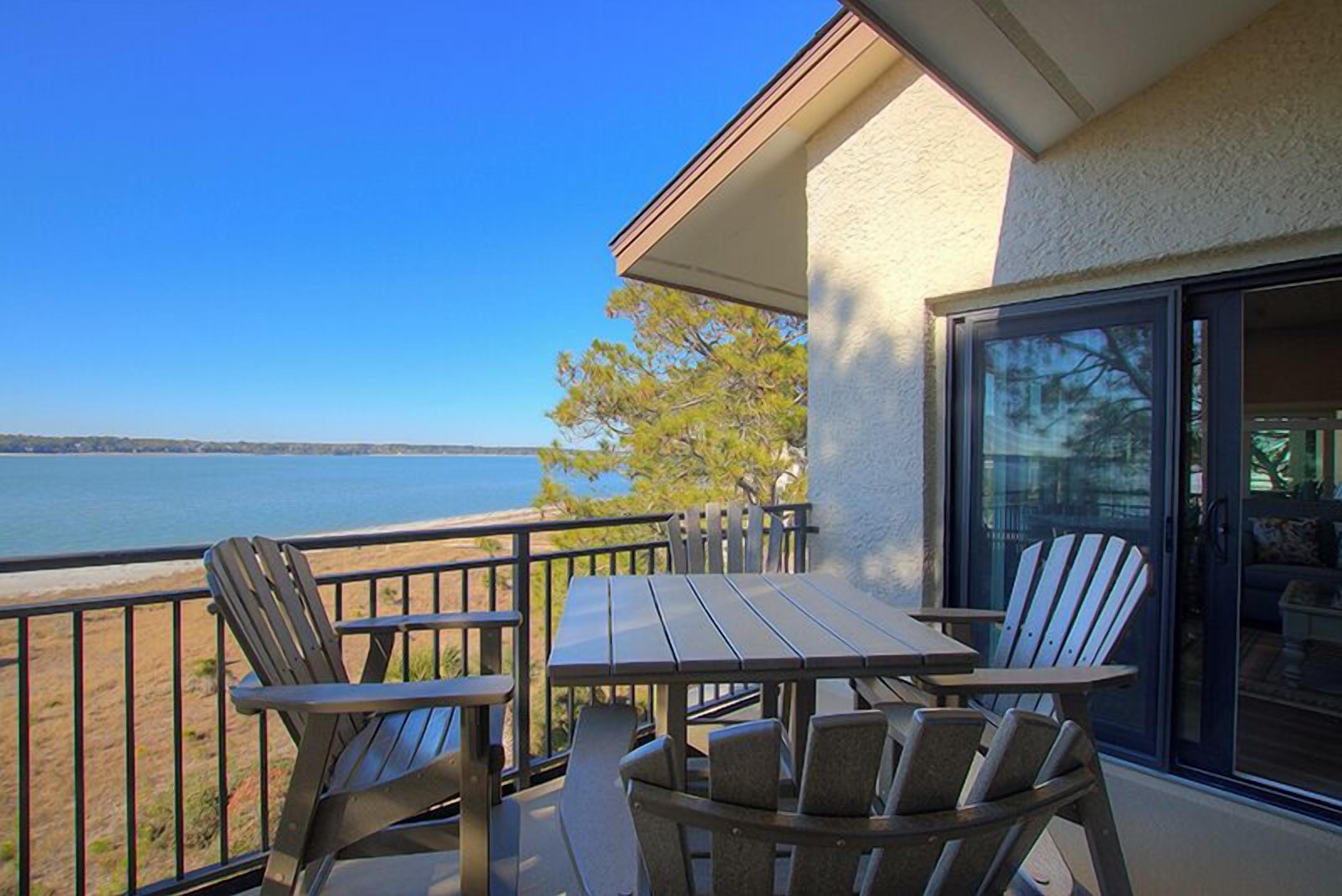 A balcony with a table and chairs overlooking a body of water.