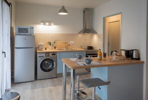 Compact kitchen with a stove, microwave, and sink, plus a dining area with a table and chairs.
