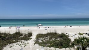 Una playa con cielos despejados, una orilla arenosa y algunas personas.