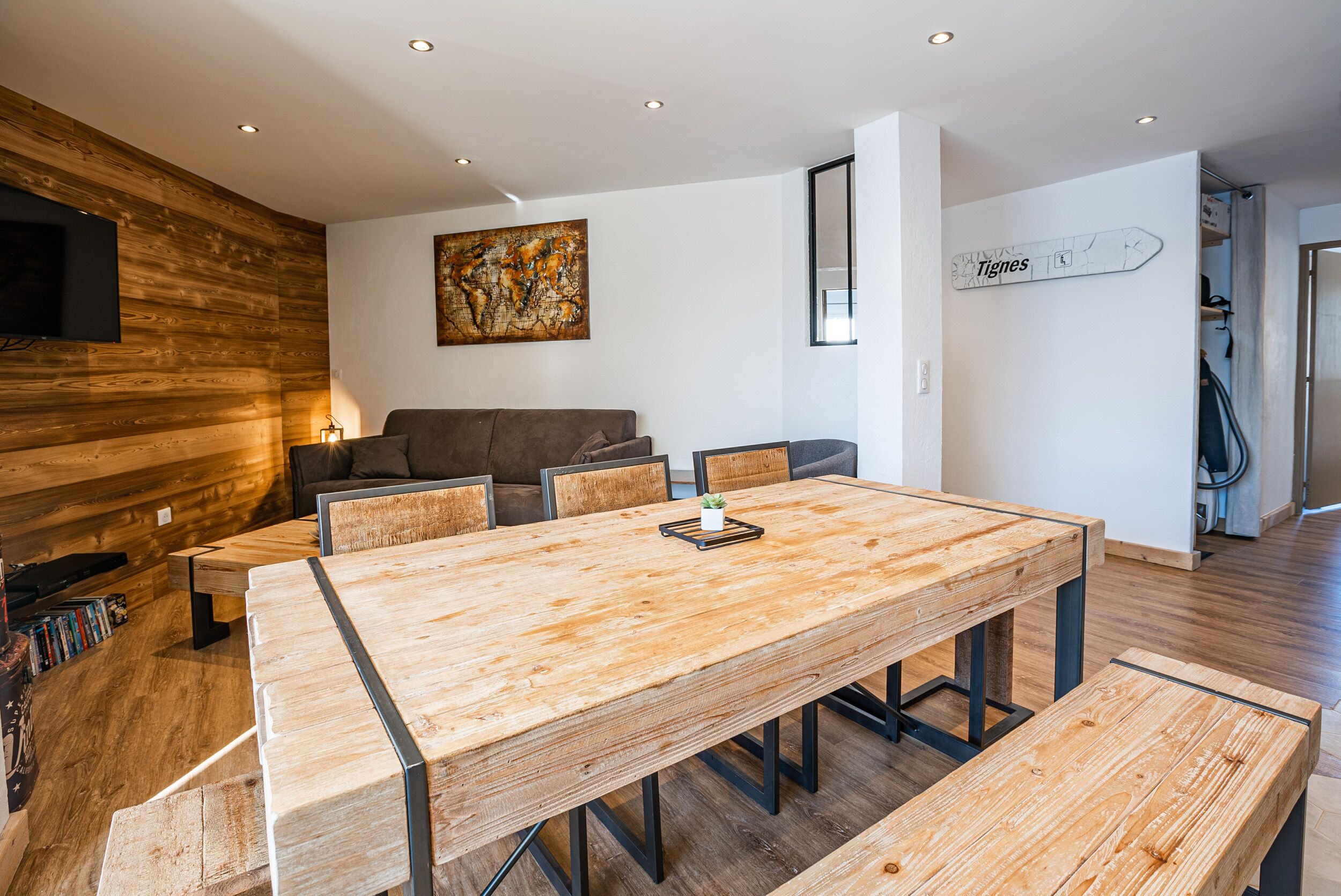 Ein modernes Wohnzimmer mit einem Holzesstisch, einer Couch und einem an der Wand hängenden Kunstwerk.