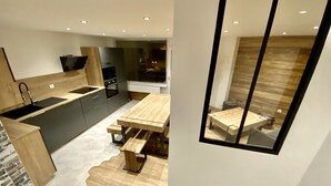 Una cucina moderna con un tavolo e una panca di legno, forno integrato e un grande specchio.