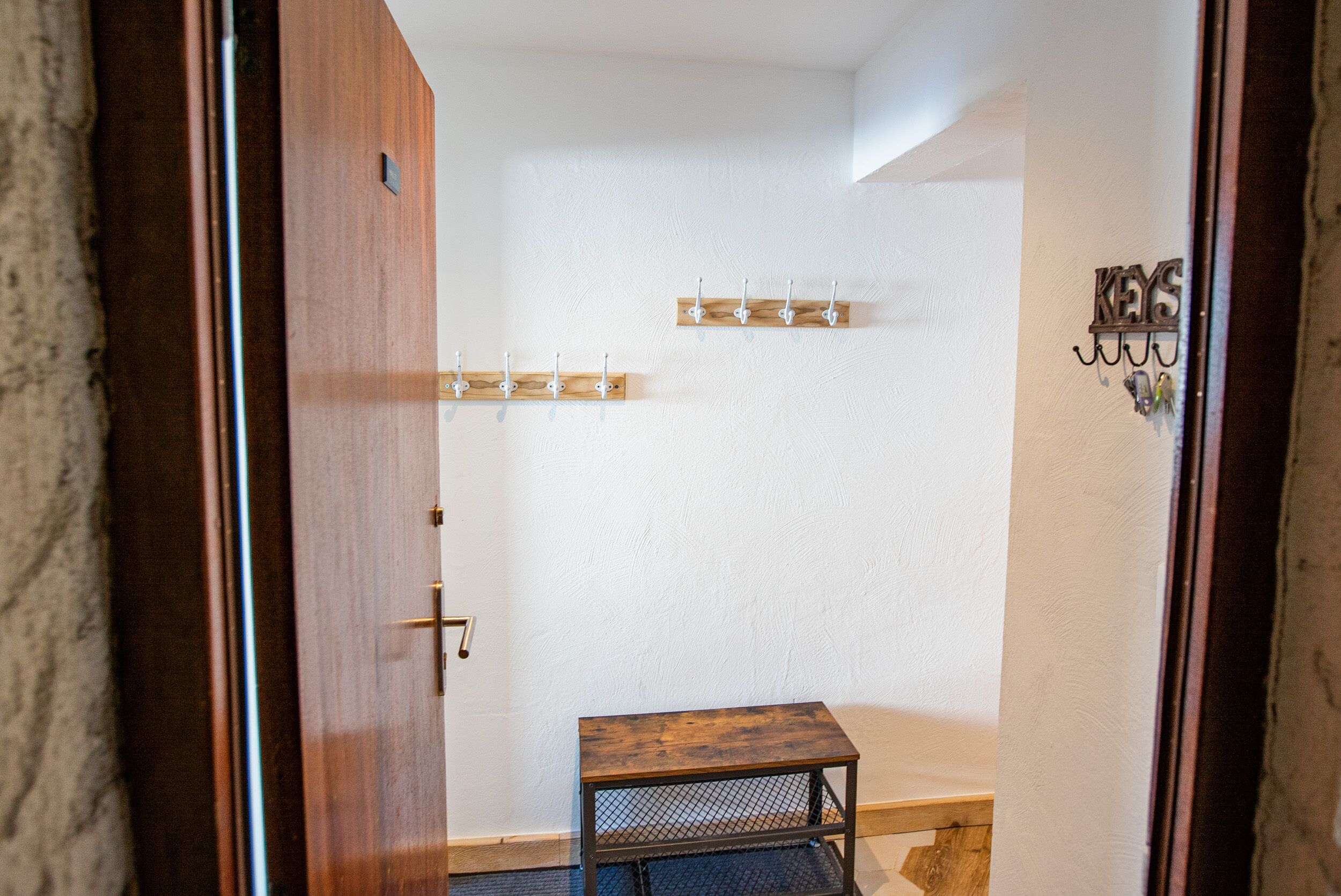 A room with a wooden door, a small wooden table, and a wall-mounted coat rack.