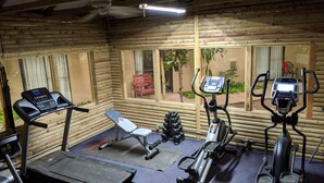 A gym with a treadmill, elliptical, and weight bench. - Atrium Inn (Fort Stockton)