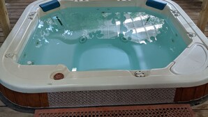 A hot tub on a wooden deck with a metal grate in front. - Atrium Inn (Fort Stockton)