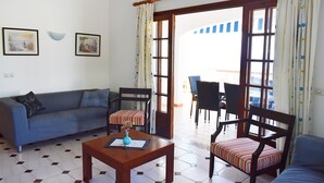 A living room with a sofa, two chairs, a coffee table, and a dining area with a table and chairs. - Villa Maria, incredible sea views, relax, swimming pool, wifi, barbecue, garden (alaior)