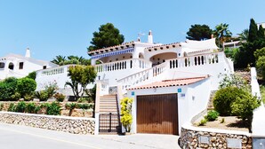 A white building with a stone wall, a wooden gate, and a garage. - Villa Maria, incredible sea views, relax, swimming pool, wifi, barbecue, garden (alaior)